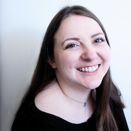 A portrait of Hayley. She is wearing a black top, and looking at the camera, smiling.